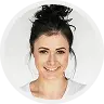 Smiling women with dark hair in a bun wearing a white top